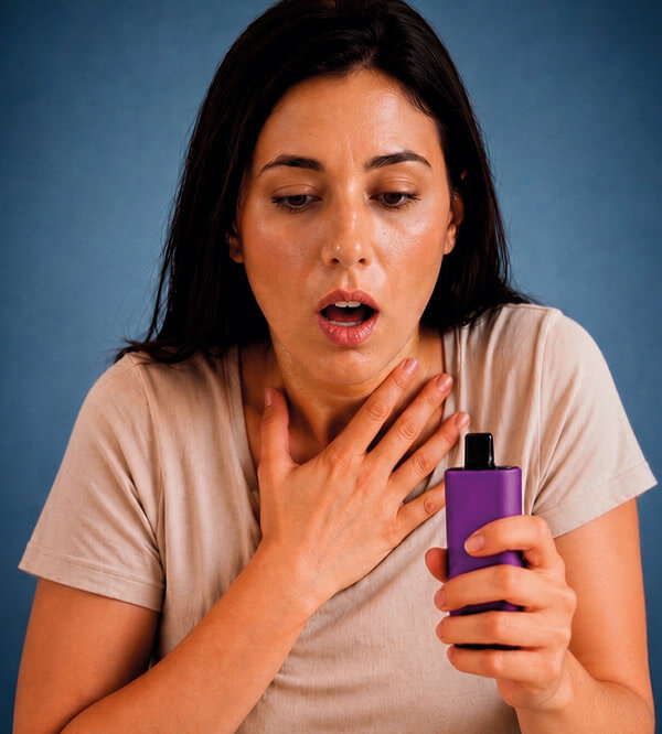 Mujer joven con dificultad respiratoria sosteniendo un vape
